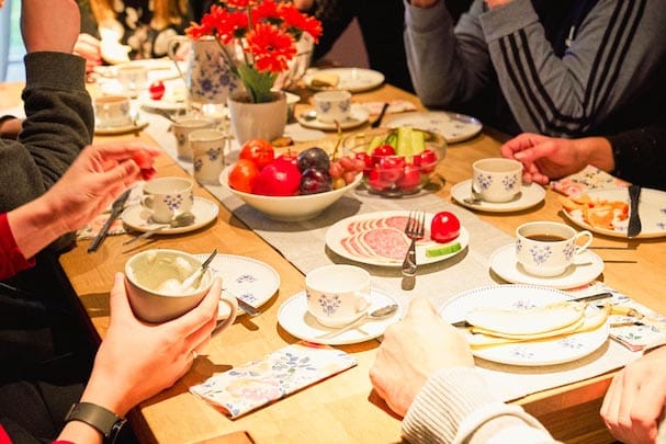 Kinder und Erwachsene zum Frühstück am gedeckten Tisch versammelt