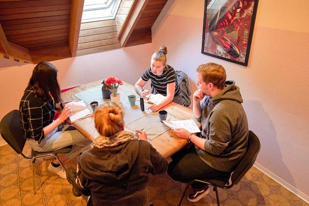 Mitarbeiter*innen bei Besprechung am Tisch im Dachgeschoss